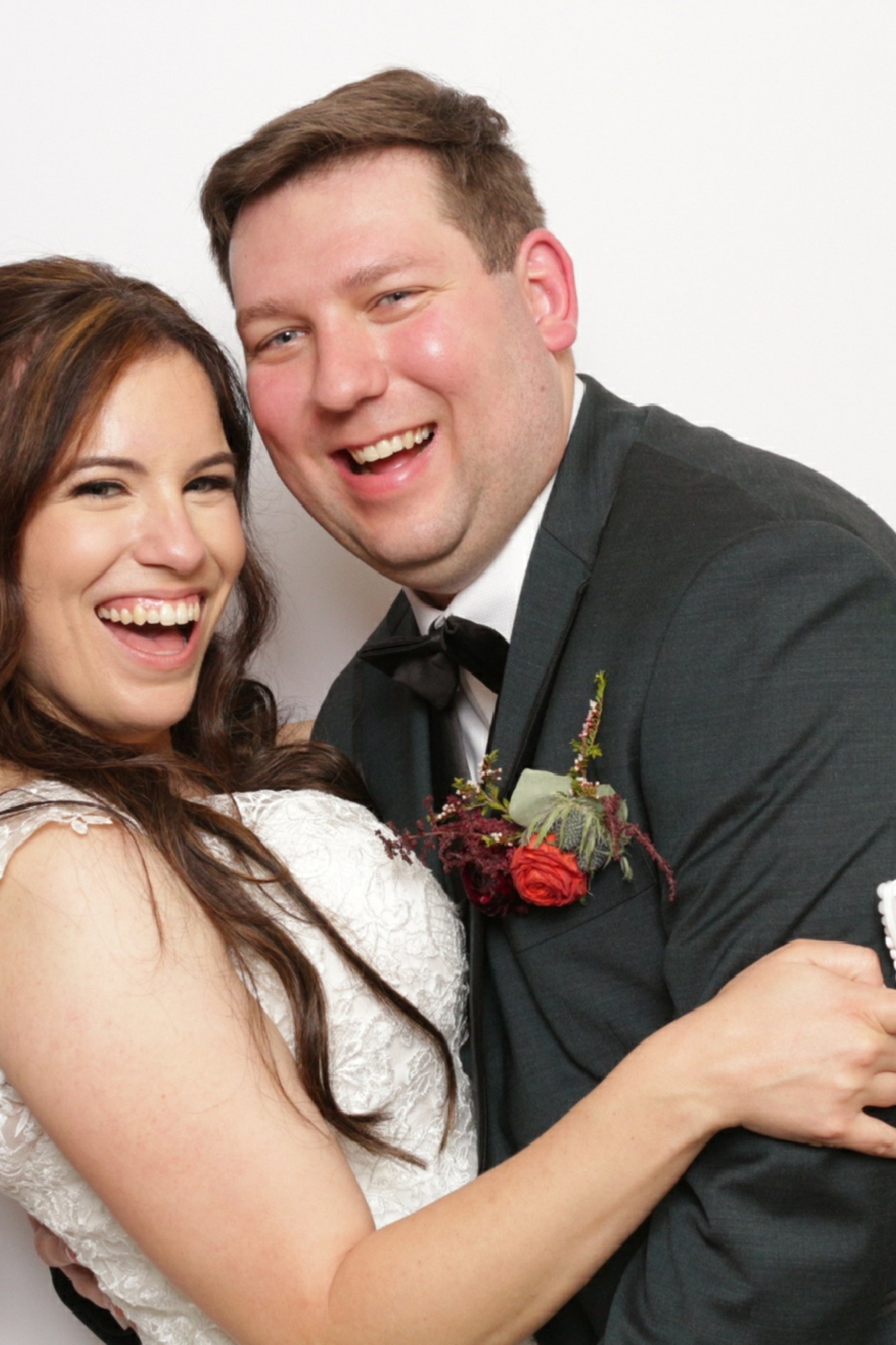 A bride and groom laughing together in the photo booth