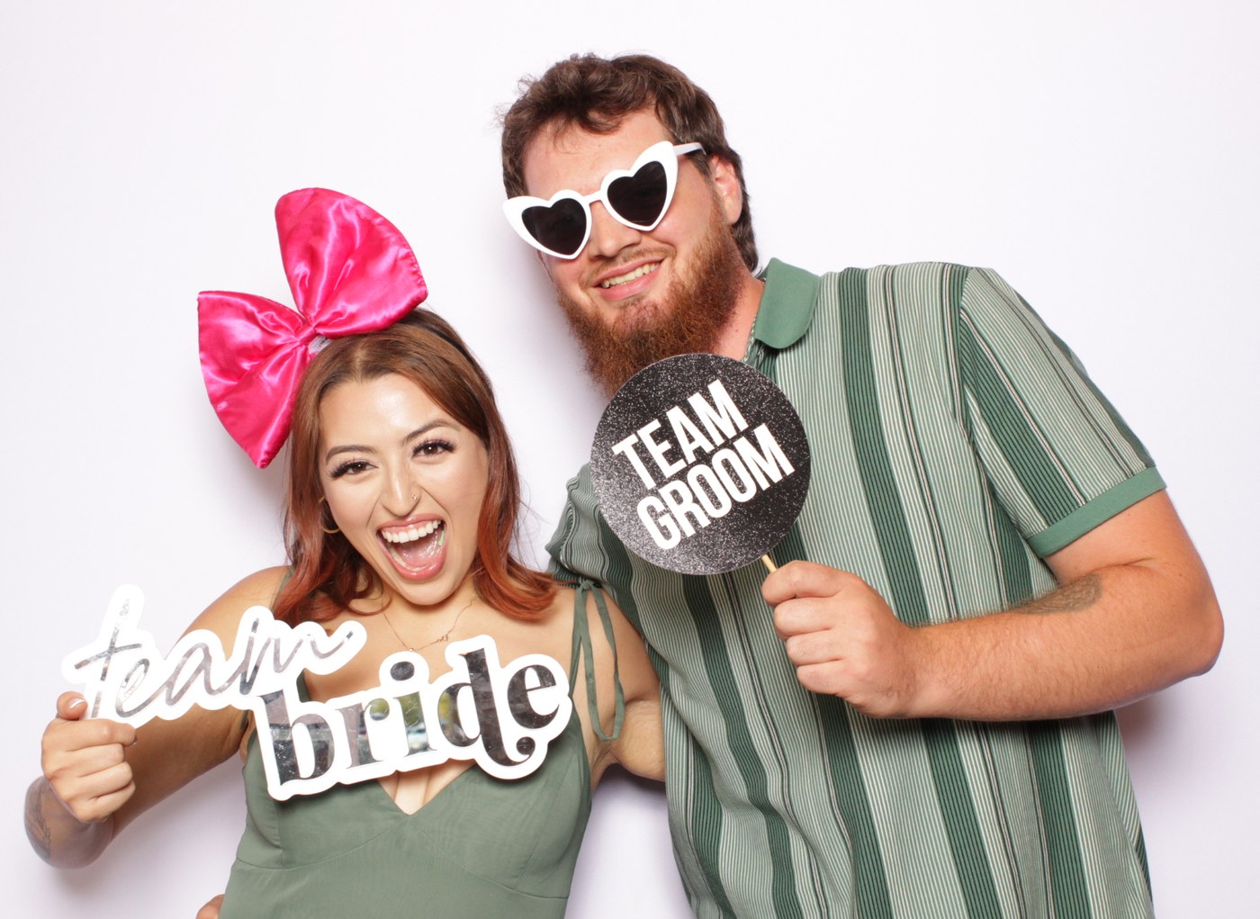 Two guests posing with bride and groom props at the booth