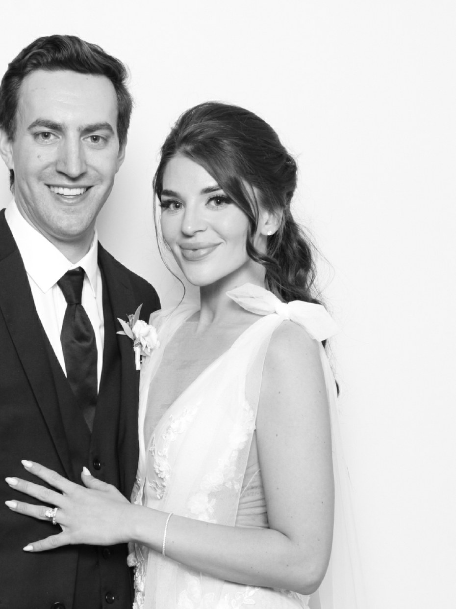 A bride and groom posing for a black and white portrait at the booth