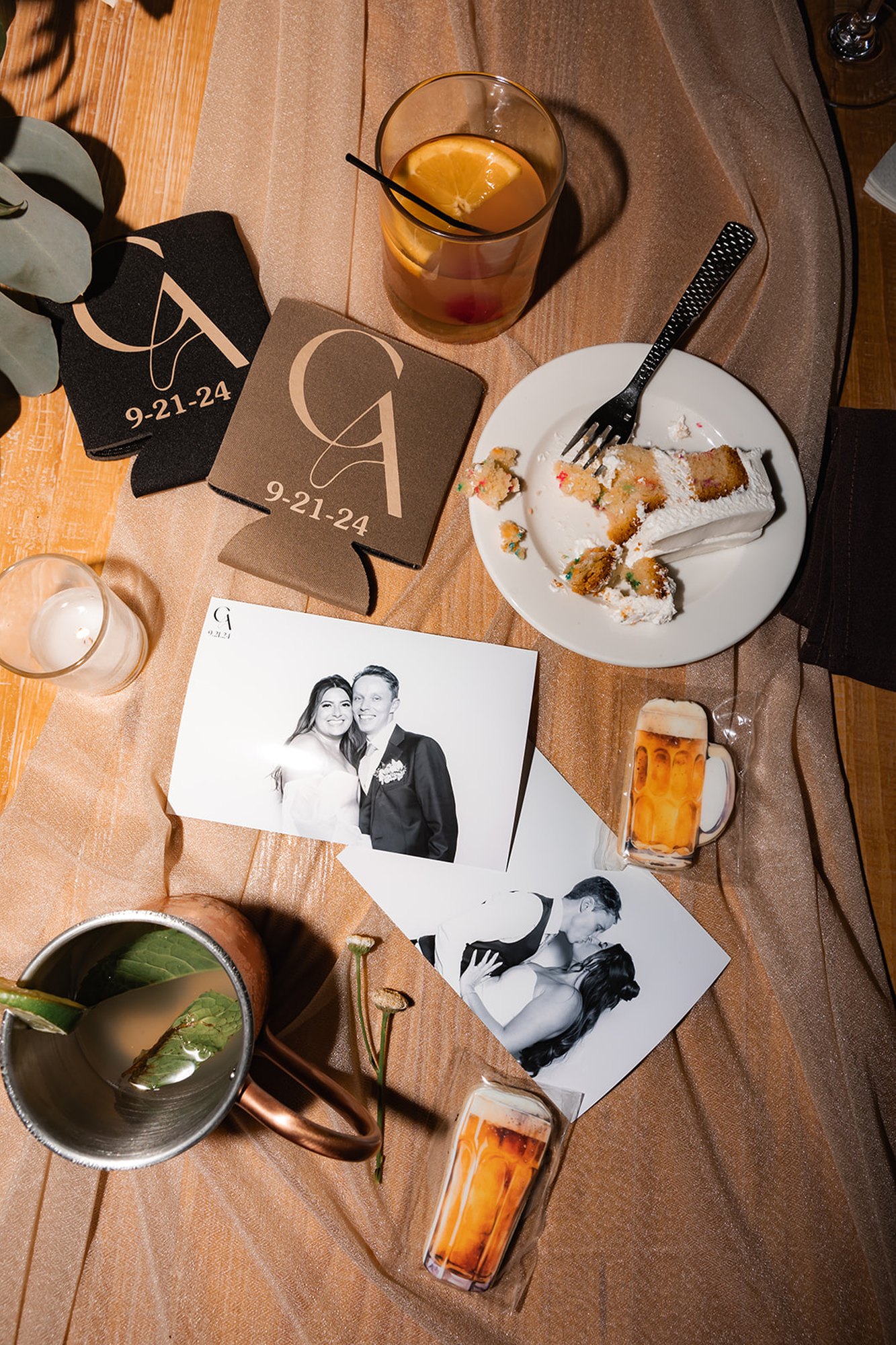 Printed photos laid out on a table beside drinks at a reception